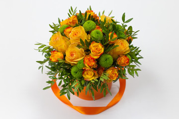 Bright bouquet of orange roses and green flowers in an orange box for hats on a light background