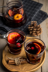 Christmas composition with spicy mulled wine and pine cones on wooden background