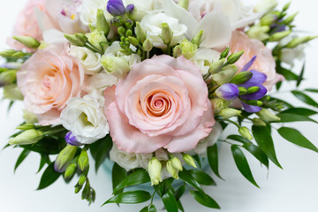 Delicate bouquet of white and pink roses and orchids with green leaves in a hat box of cerulean color on a light background