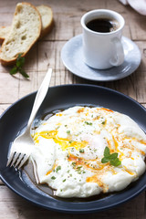 Cilbir, poached egg in yogurt with spiced butter and herbs, served with bread and a cup of coffee.
