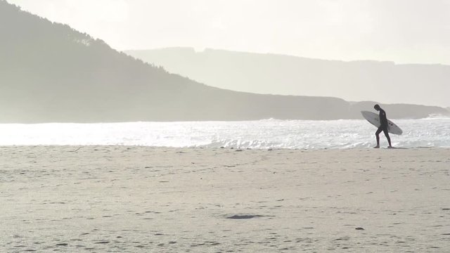 Hombre con tabla de surf en la playa