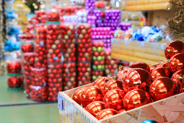 Fototapeta na wymiar Blurred image of red balls in the box and Christmas and New Year decorations in the store, defocused background of the market, winter concept