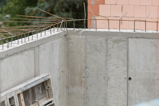 Baustellendetails mit frisch gegossener Betonkellerwand und Armierungseisen