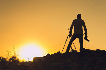 Silhouette of black photographer at sunset