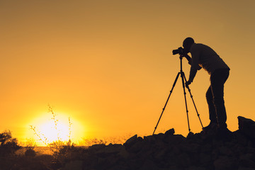 Silhouette of black photographer at sunset