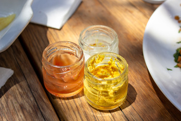 Close-up shoot of ketch-up, mayonnaise, mustard in the cups under clean light