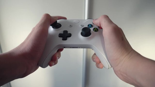 Point of view of teenage gamer holding controller to play video games, Video game console controller in male hands