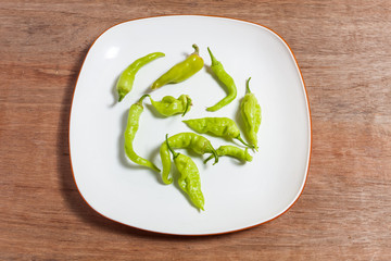 Top view of fresh green chilies (Green Pepper) in white plate on wooden background