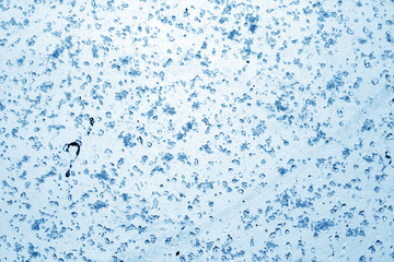 Snow and water on blurred window in navy blue tone.