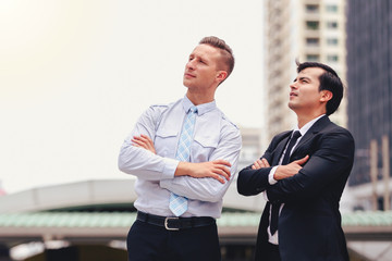 Two business men standing looking in city