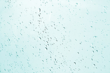 Blured water drops on window in cyan tone.