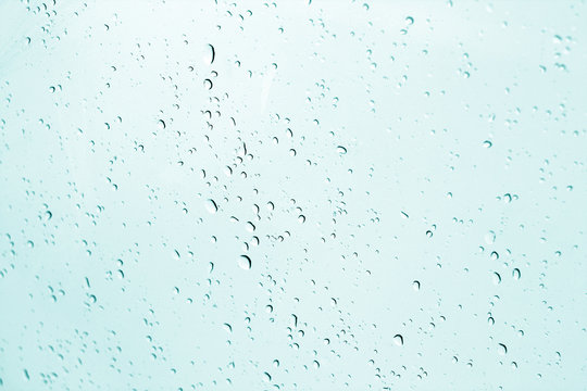 Blured water drops on window in cyan tone.