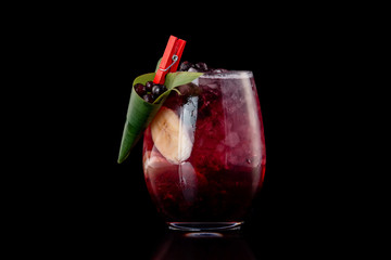 Glass of berries sangria with red wine, black currant, lemon and banana isolated at black background.