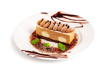 Plate with sweet layered cake dessert decorated with mint and chocolate cream as a children menu funny cheesecake isolated at white background.