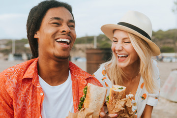 Couple dating and eating sandwiches at a beach picnic