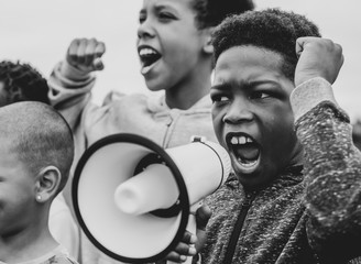 Young boy shouting on a megaphone in a protest - obrazy, fototapety, plakaty