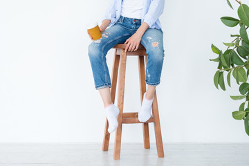 woman sitting on high wooden stool with coffee cup. relaxed leisure and casual lifestyle. white...
