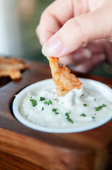 Hand dipping fried calamari into Tartar sauce