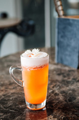 A glass of Jasmine tea orange cocktail with fluffy foam on top