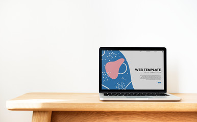 Laptop showing website template on a wooden table