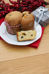 Italian Christmas cake called Panettone with a slice on a plate on wooden table. Traditional food to celebrate Christmas holidays