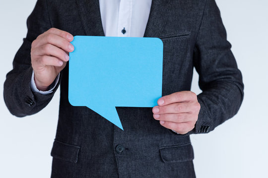 Man Holding Blue Paper In Shape Of Empty Speech Bubble. Icon Of Social Media Communication And Ideas.