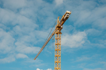 Construction crane tower against a blue sky. Yellow construction crane against the blue sky with...