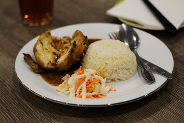Checken Roasted, served with rice and salad on the plate, on wood table