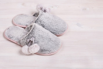 Slippers with fur on wooden background.