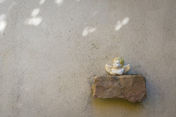 Small angel sculpture placed on brick on wall