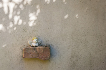 Small angel sculpture placed on brick on wall