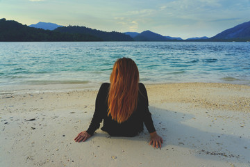 Back of Asian woman sitting and relaxing on beach