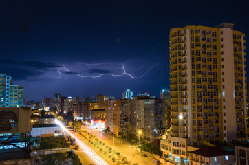 Fototapeta na wymiar Lightning storm over city in purple light