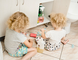 Unattended children play quietly at bathroom with dangerous household chemicals. Safety hazard at...