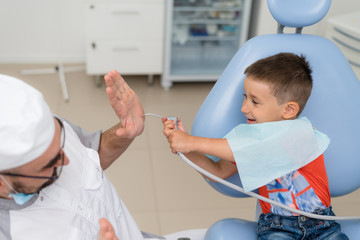 the dentist plays with a small patient so that he is not afraid to treat his teeth