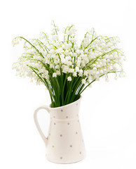 Bouquet of white flowers Lily of the valley (Convallaria majalis) also called: May bells, Our Lady's tears and Mary's tears in a white dotted jug shaped vase isolated on white.