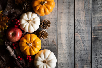 Top view of  Autumn maple leaves with Pumpkin and red berries on old wooden background. Thanksgiving day concept.