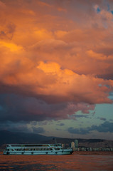 Majestic colorful cloud landscape over the sea and city at sunset. Izmir, Turkey.