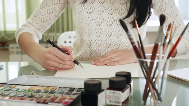 Young Woman Artist Drawing Watercolor Paints At The Table. 