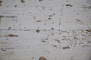 Thin layer of chapped old white paint on wooden surface