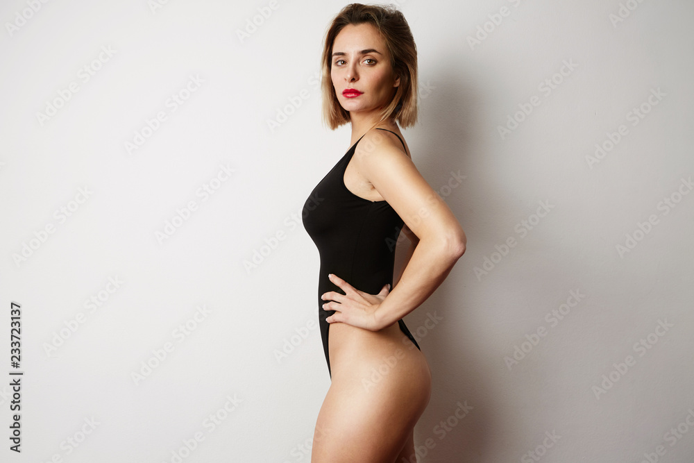 Wall mural sexy girl in black swimsuit posing on white background. space for text.