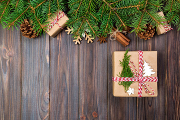 Christmas background with fir tree and gift box on wooden table. Top view with copy space for your design
