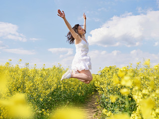 Happy woman jumping with raised hands outdoor.