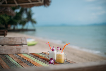 fruit cocktails decorated with orchids on the table of the beach bar against the background of the sea. Healthy drinks