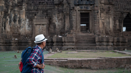 Fototapeta na wymiar Senior man Asian with backpack are walking at Phra Prang Sam Yot. Ancient and historical attractions and one of the most important archaeology of Lopburi province thailand. Travel, Tourist Concept
