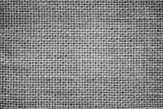 Close-up of a burlap jute canvas full frame background with vignetting in black and white.