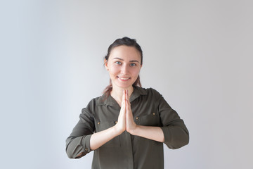 Positive pretty Caucasian girl pressing hands in mudra gesture. Young white woman finding happiness. In harmony with the world concept