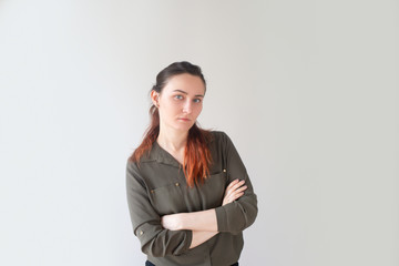 Obraz premium Tired young Caucasian woman crossing arms and looking at camera. Attractive female assistant displeased with workload. Too many duties concept