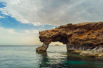 Naklejka premium Natural arch. Filfla island under arch. Malta