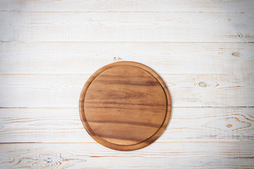 Round pizza cutting board on kitchen white wooden table background. Top view and copy space.